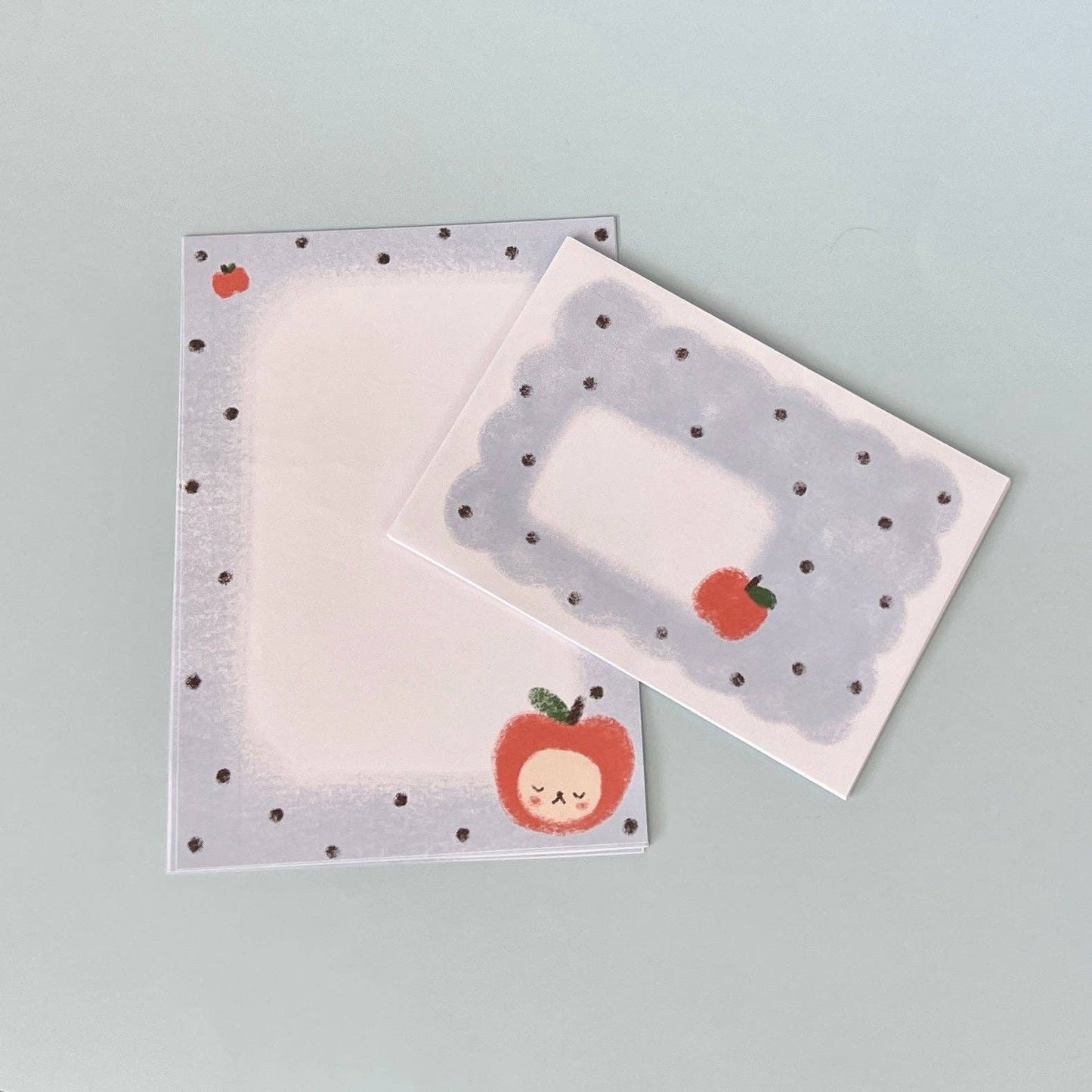 letter writing set with polka dot borders and apple designs on a light gray background