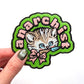 Embroidered patch with a cat design and text held by a hand on a white background