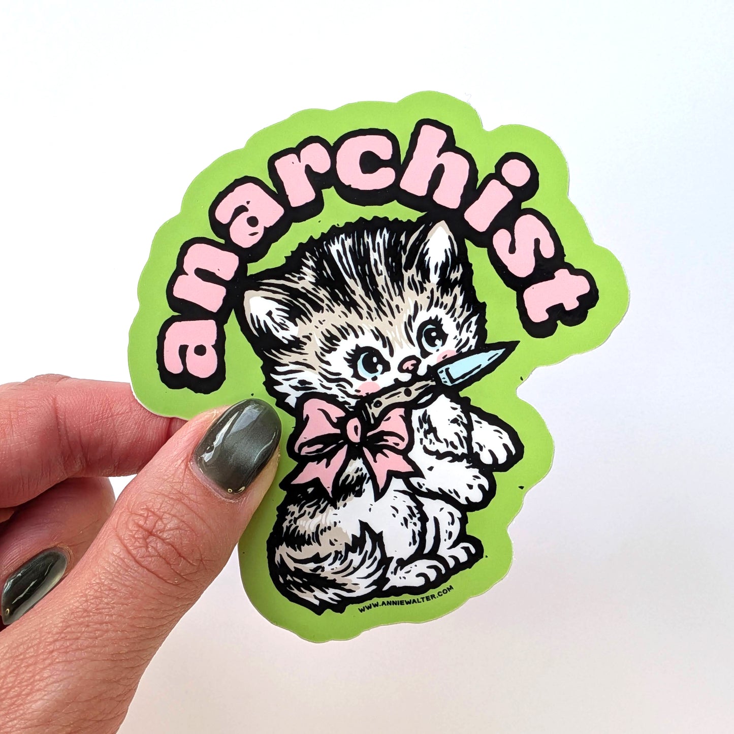 Hand holding a green sticker of a cat design with the text 'anarchist'