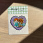Shellflower glitter sticker with two small characters on a checkered background