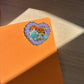 Orange background with a heart-shaped sticker featuring two sylvanian characters on a wooden surface.