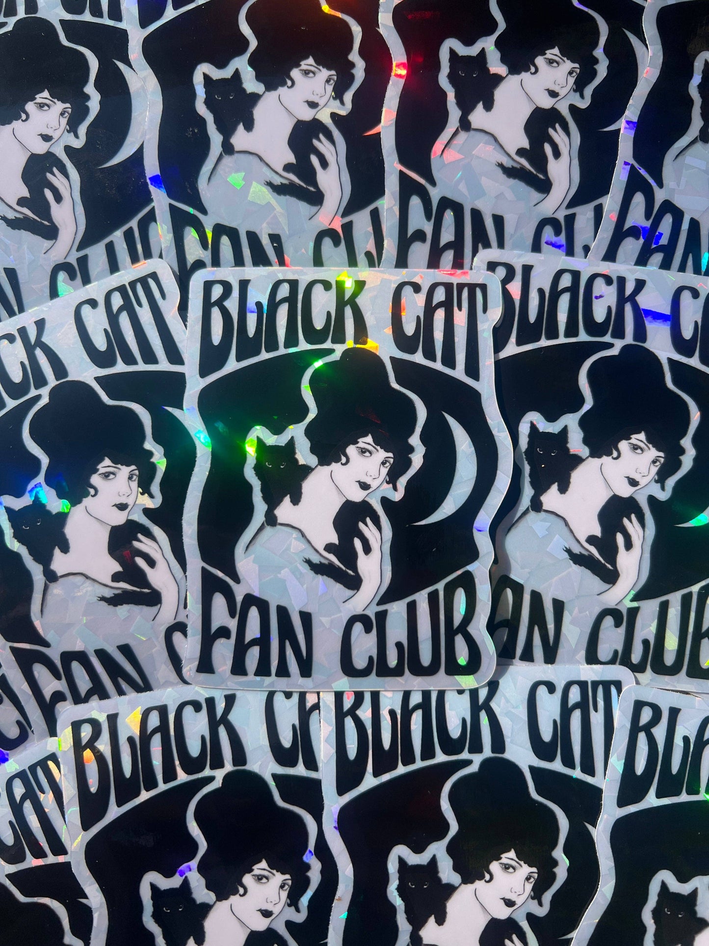Stickers with a woman's silhouette and 'Black Cat Fan Club' text on a reflective surface.