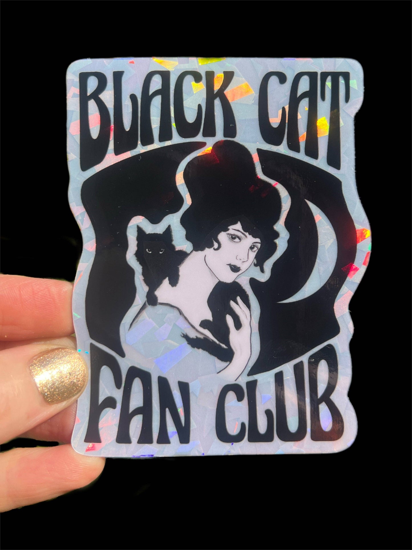 Holographic sticker with a woman and black cat design, labeled 'Black Cat Fan Club', held by a hand.
