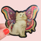 Sticker of a cat with butterfly wings held by a hand on a pink background