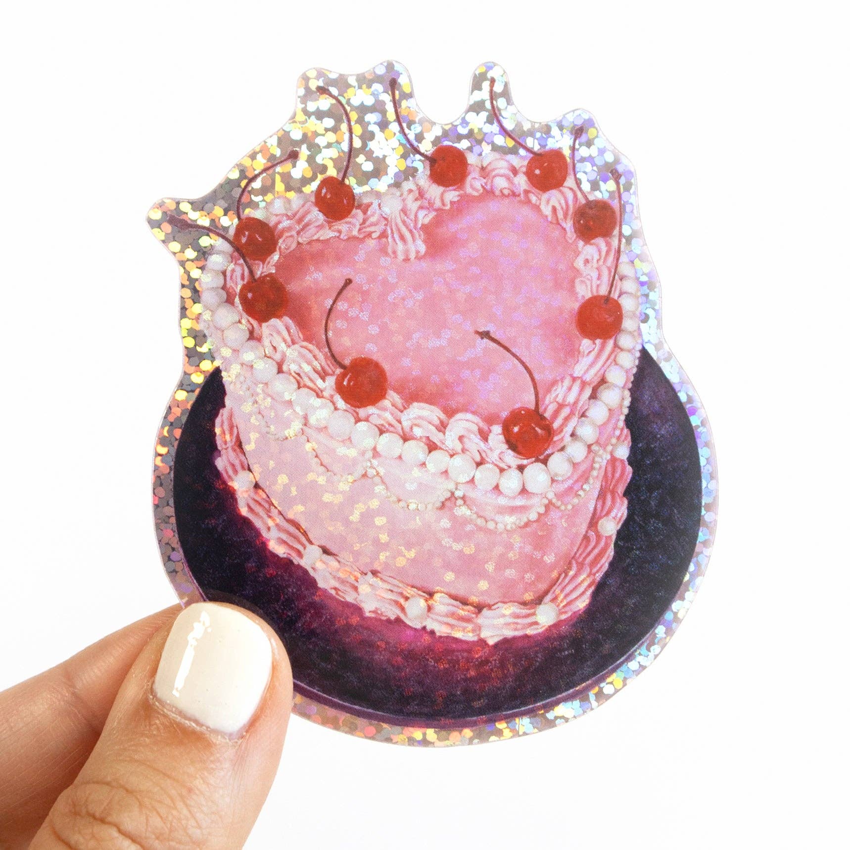 Glitter sticker of a pink cake with cherries held by a hand on a white background