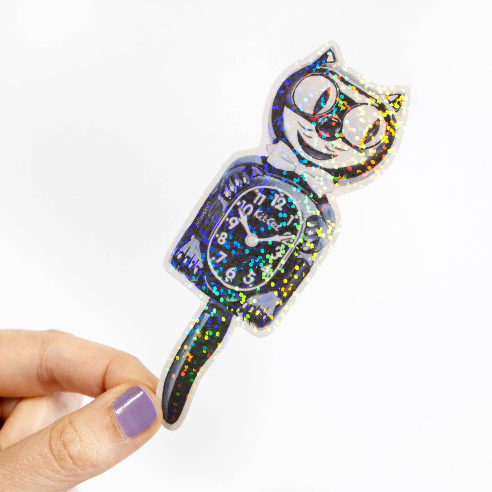 Cat-shaped clock with glittery finish held by a hand on a white background