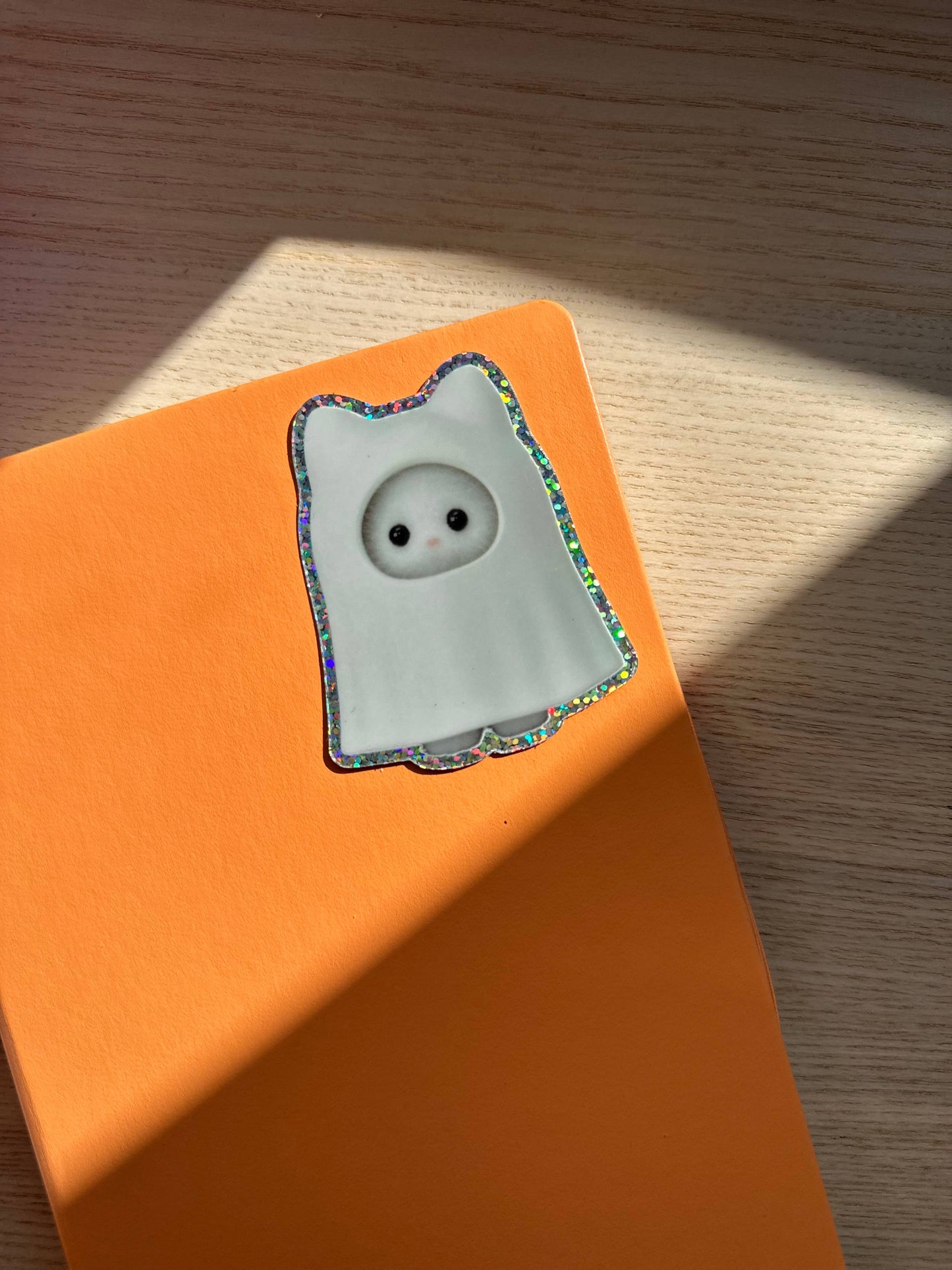 Cat sylvanian ghost glitter sticker on an orange background
