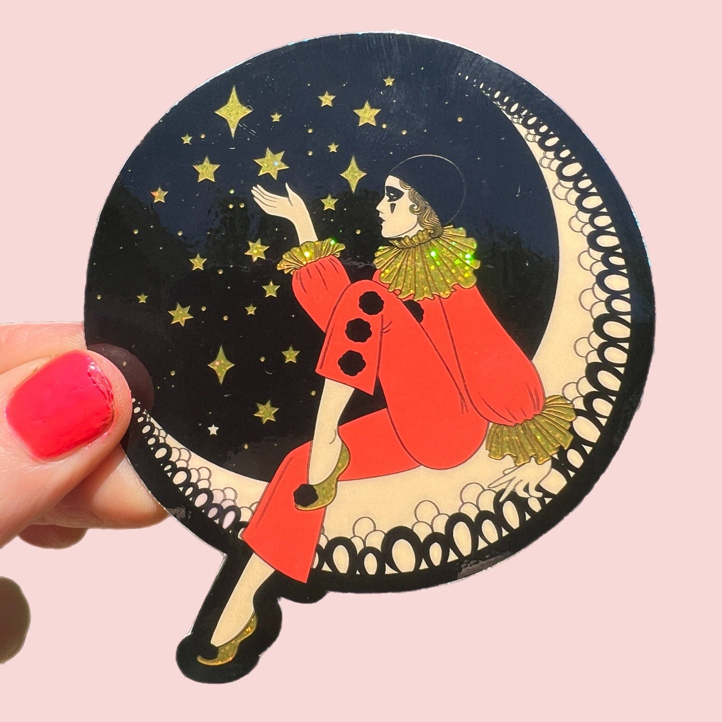 Decorative sticker with a person in a red coat and gold accents sitting on a crescent moon, surrounded by stars, held against a pink background.