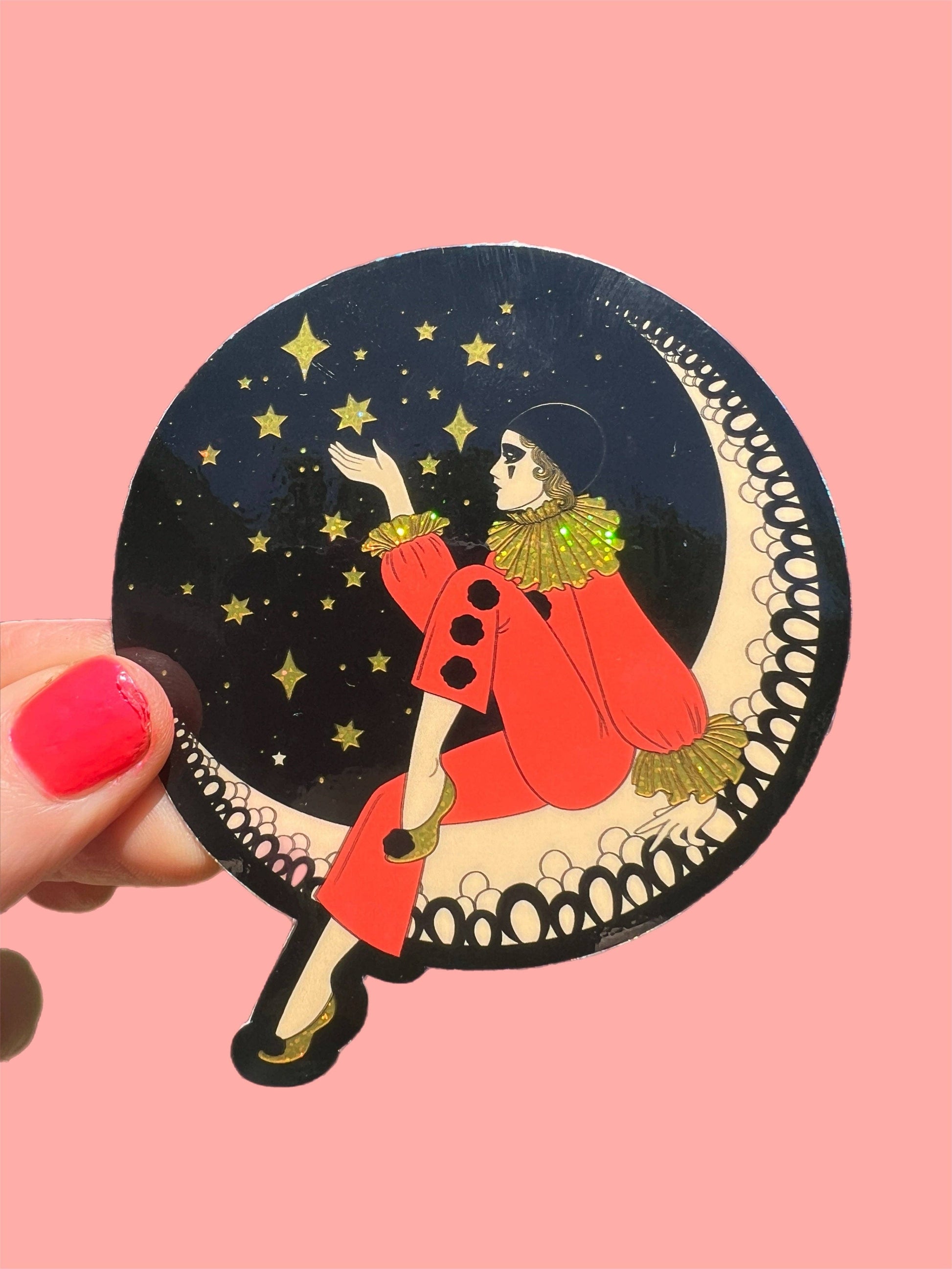 Sticker of a person in a red coat sitting on a crescent moon with stars, held against a pink background.