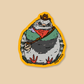A die-cut sticker featuring a cartoon pigeon dressed in western attire, including a cowboy hat, red bandana, green vest, and a guitar, set against a solid beige background.