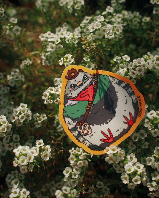 A die-cut sticker featuring a cartoon pigeon wearing a red bandana and green jacket, placed on a bed of small white flowers. The sticker has a yellow border and the text 'OOD OTOO' printed on the right side.