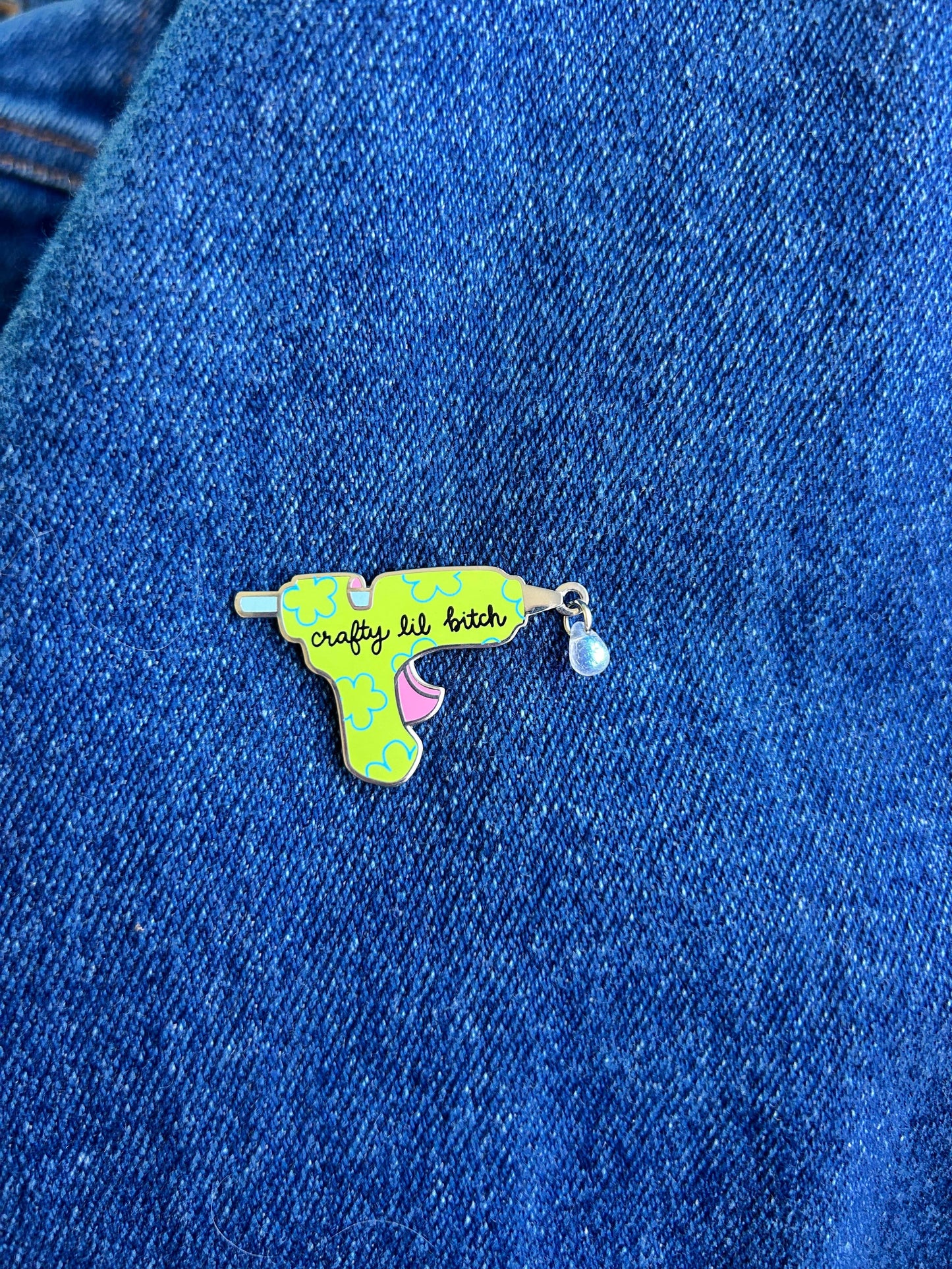 Colorful glue gun pin on a blue denim background