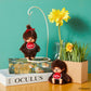 Two small brown plush toys with red bows on books against a teal background