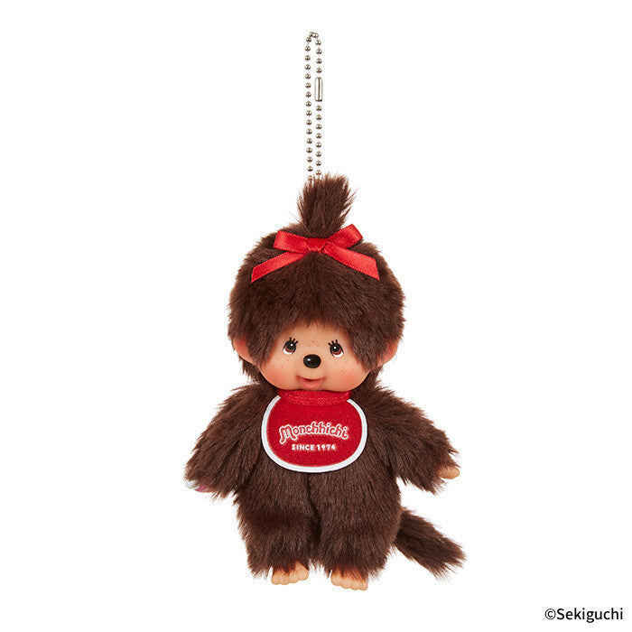 Brown plush Monchhichi keychain with a red bow and visible brand logo on a white background