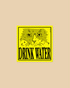 A square yellow sticker or sign featuring a stylized cat face above the words “DRINK WATER” in bold black letters, centered on a plain beige background.