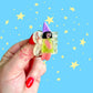 Hand holding a small fairy hair clip against a blue background with yellow stars