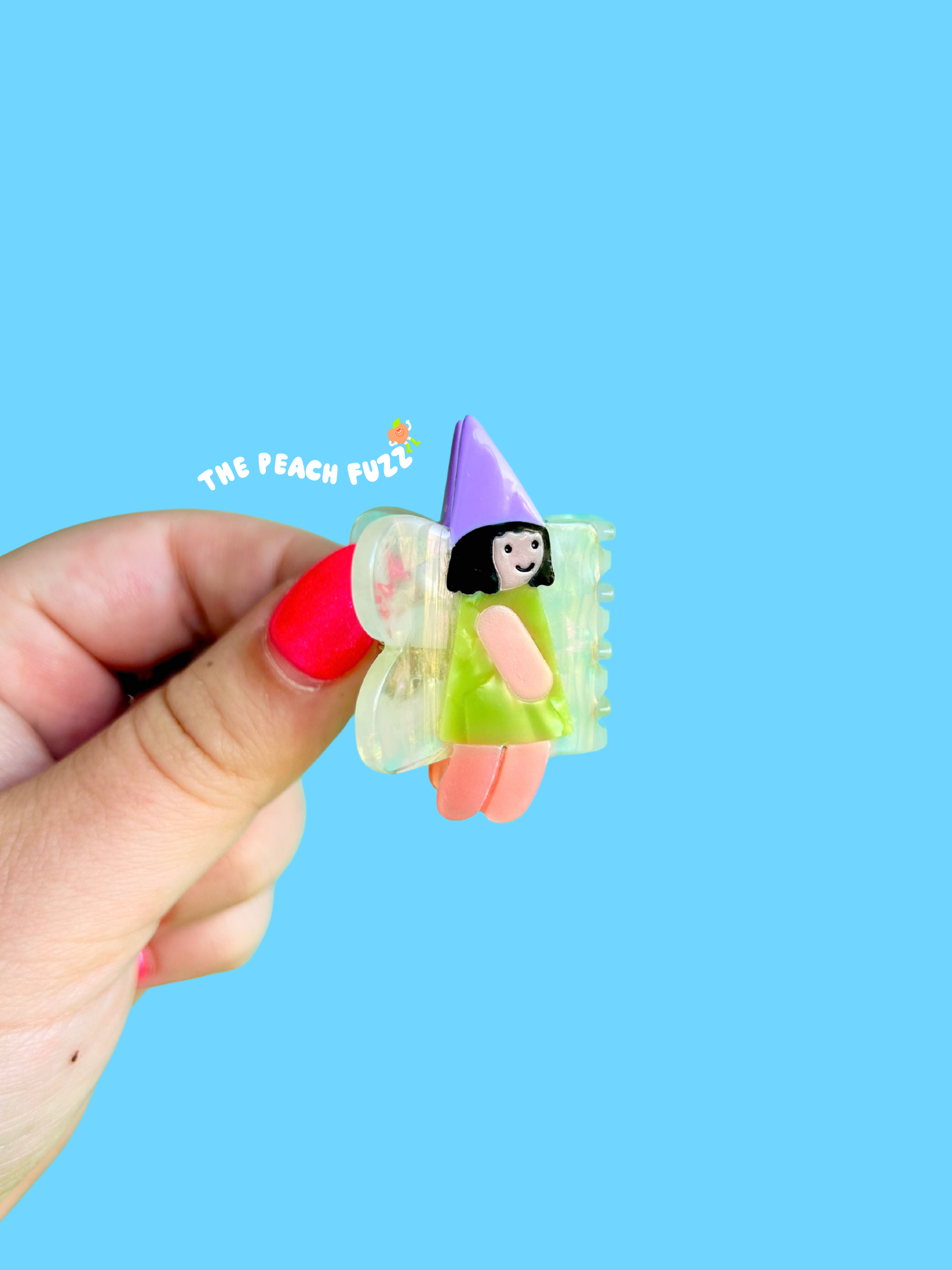 Hand holding a small fairy-themed product with a blue background