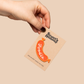 Hand holding a card with a foodie-themed badge on a beige background