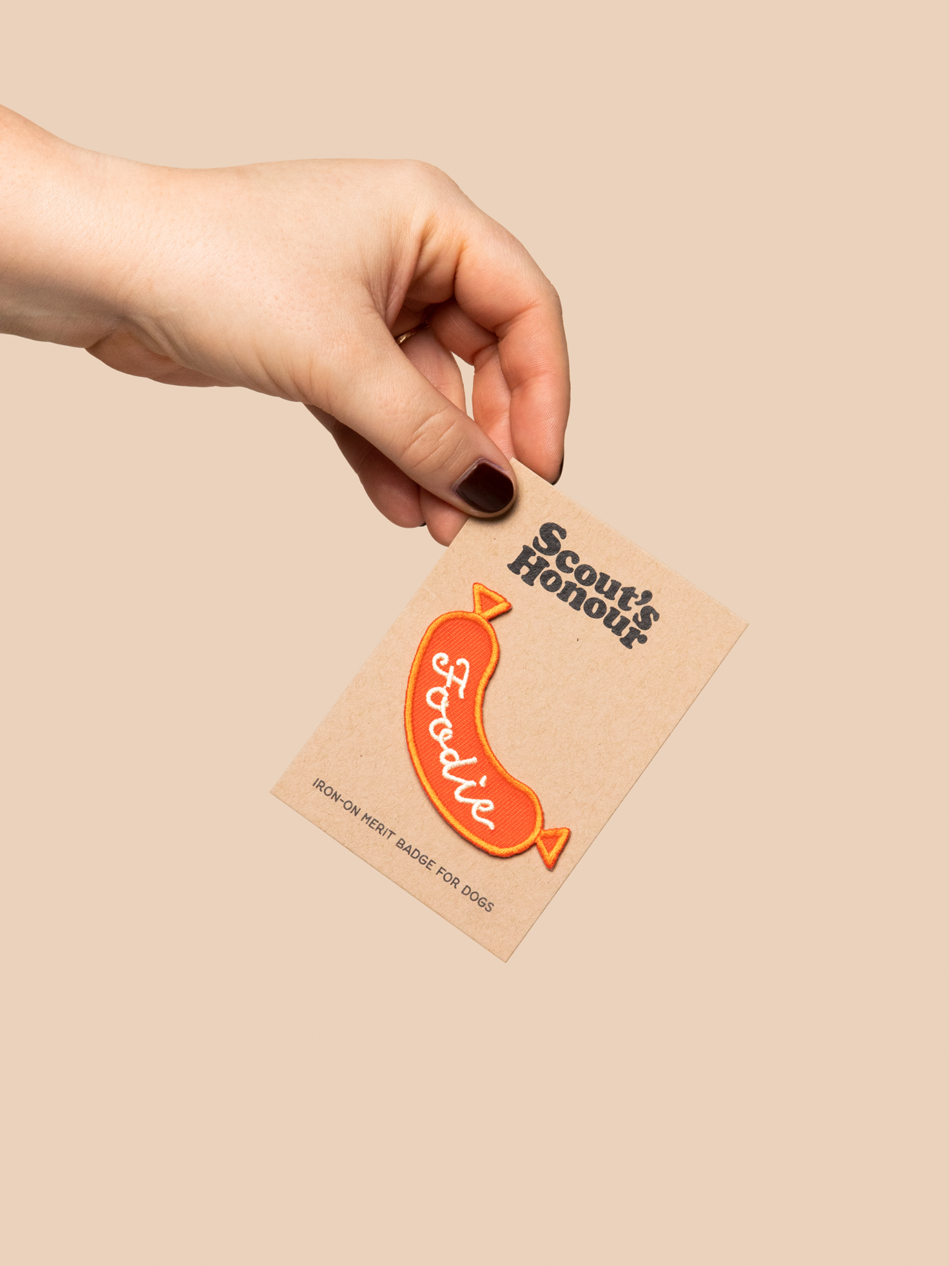 Hand holding a card with a foodie-themed badge on a beige background