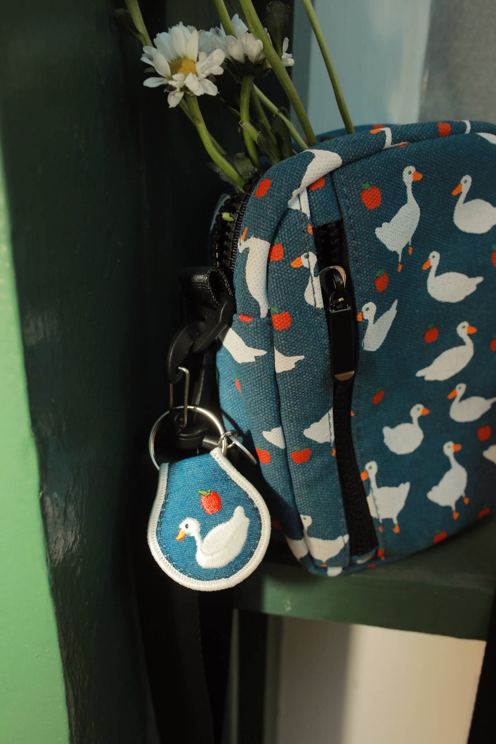 Small blue pouch with duck pattern and matching keychain on a green surface