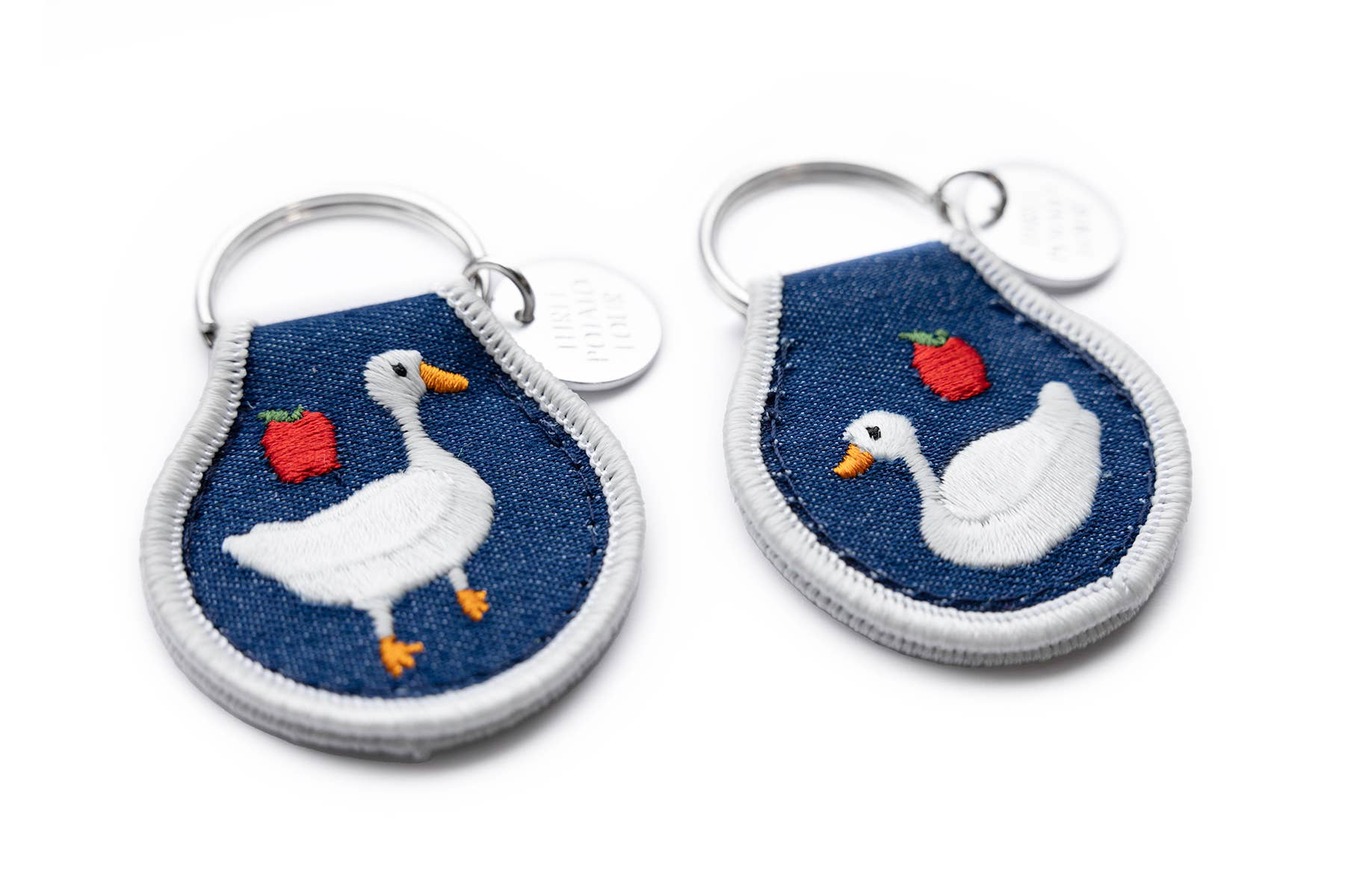 Two keychains with ducks and apples on a blue background