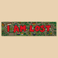 A rectangular sticker or sign featuring the phrase 'I AM LOST' in large red letters over a whimsical green map illustration with cartoon-style roads, houses, and trees, shown on a solid beige background.