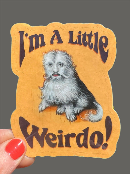 Sticker with a dog illustration and text 'I'm A Little Weirdo!' held by a hand.