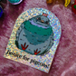 A sticker featuring a cartoon pigeon with the text 'Justice for pigeons!' on a holographic background, placed on a purple textured surface with other colorful objects partially visible around the edges.