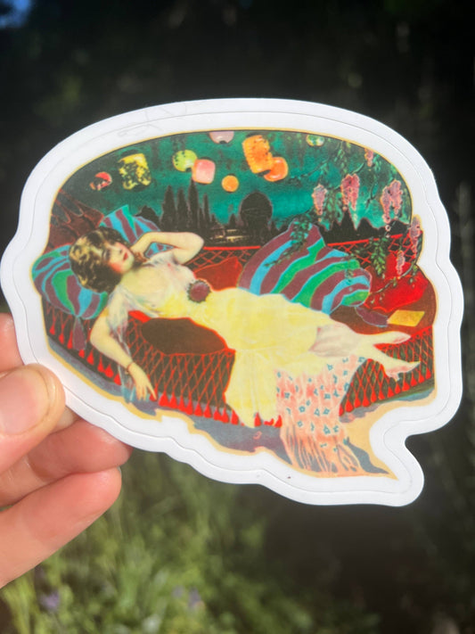 Colorful sticker of a woman lounging on a chair with a vibrant background held by a hand.