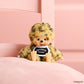 Plush toy with a fur hat and black shirt on a pink background