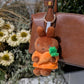 Plush keychain of Melanie holding a carrot attached to a brown handbag