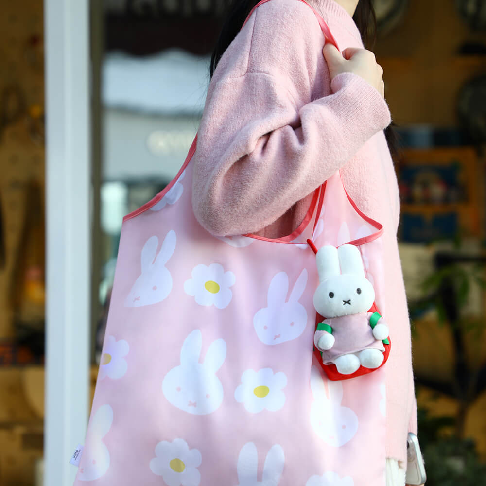 person holding a pink tote bag on their shoulder with a plush miffy hanging to the side