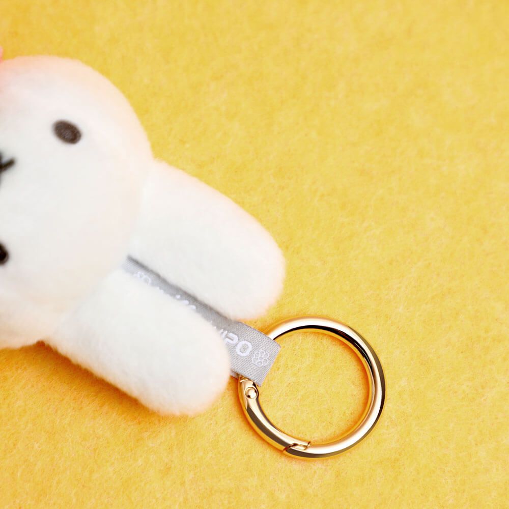 White plush Miffy with a gold ring on a yellow background