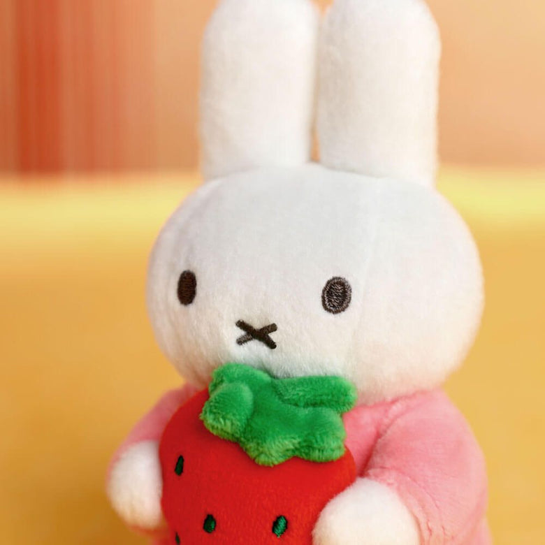 White plush Miffy with a strawberry and green leaf on a yellow background
