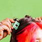 Person with red hair getting a green hair dyeputting a hair lip to their hair against a green background