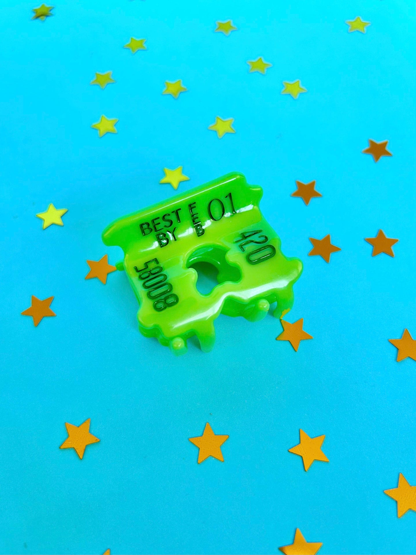 Green bread hair clip with text on a blue background with yellow stars
