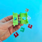 Hand holding a green plastic hair clip against a blue background