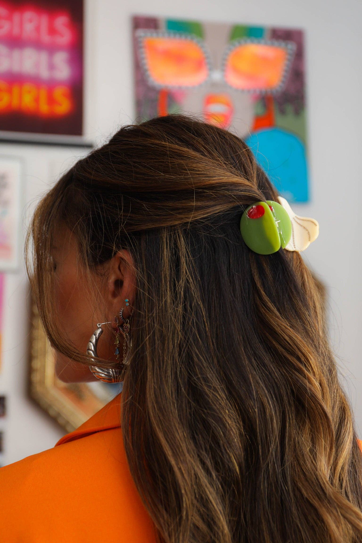 Person with a colorful hair clip in an indoor setting with artwork on the wall.