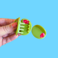 Mini olive hair claw clip, held by a hand against a blue background