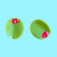 Two green olive hair clips with red centers on a light blue background