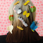 Person with various colorful hair accessories on a pink patterned background