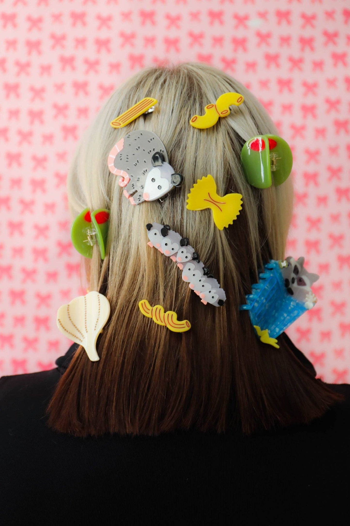 Person with various colorful hair accessories on a pink patterned background