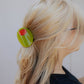 Person with a green olive hair clip in their hair against a white background