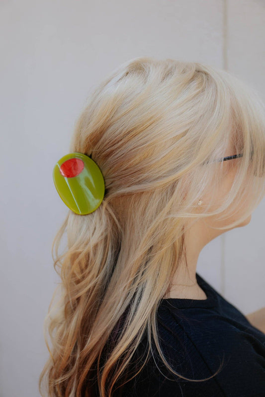 Person with a green olive hair clip in their hair against a white background