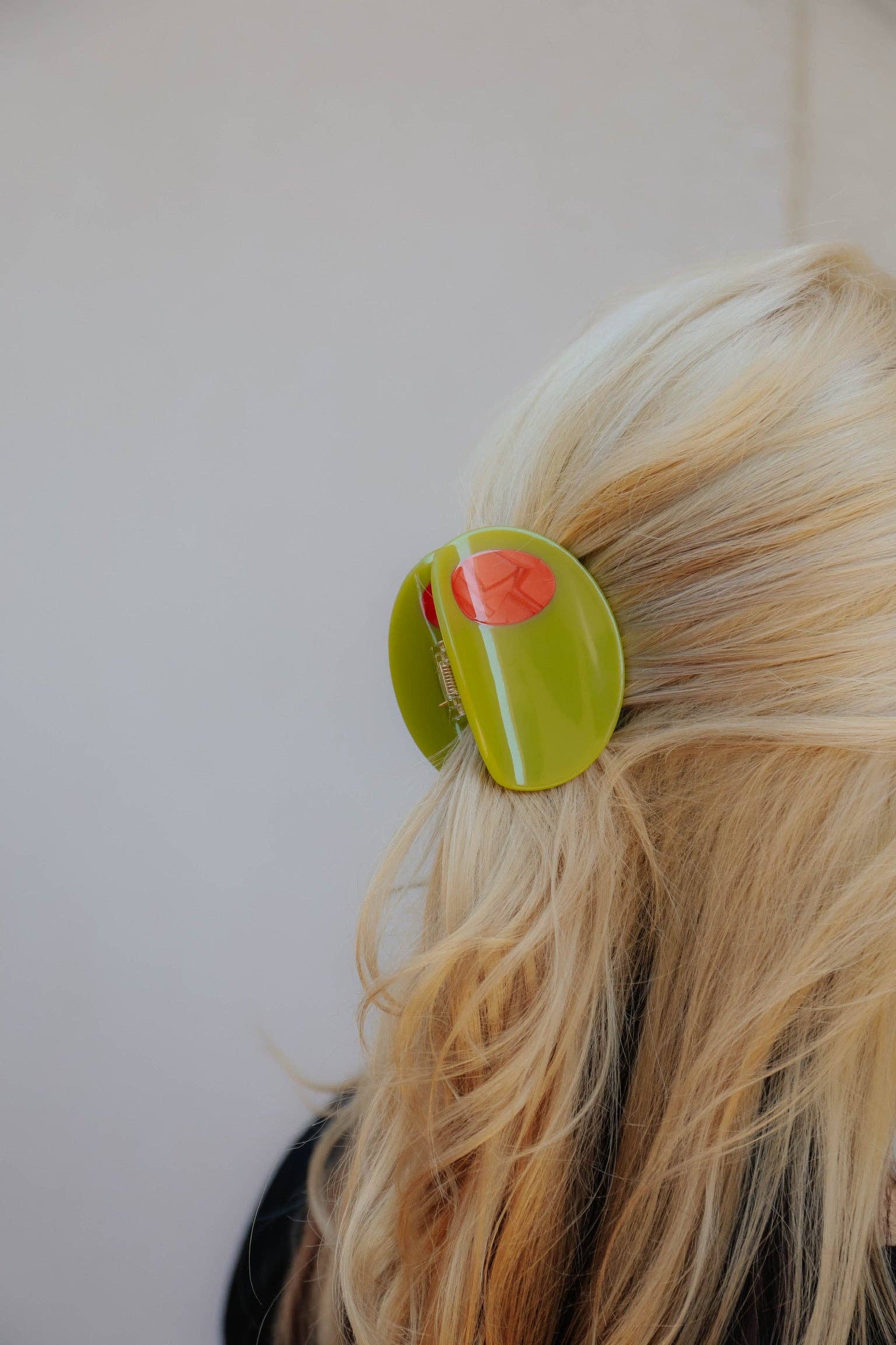 Person wearing a green olive hair clip in their hair on a plain background