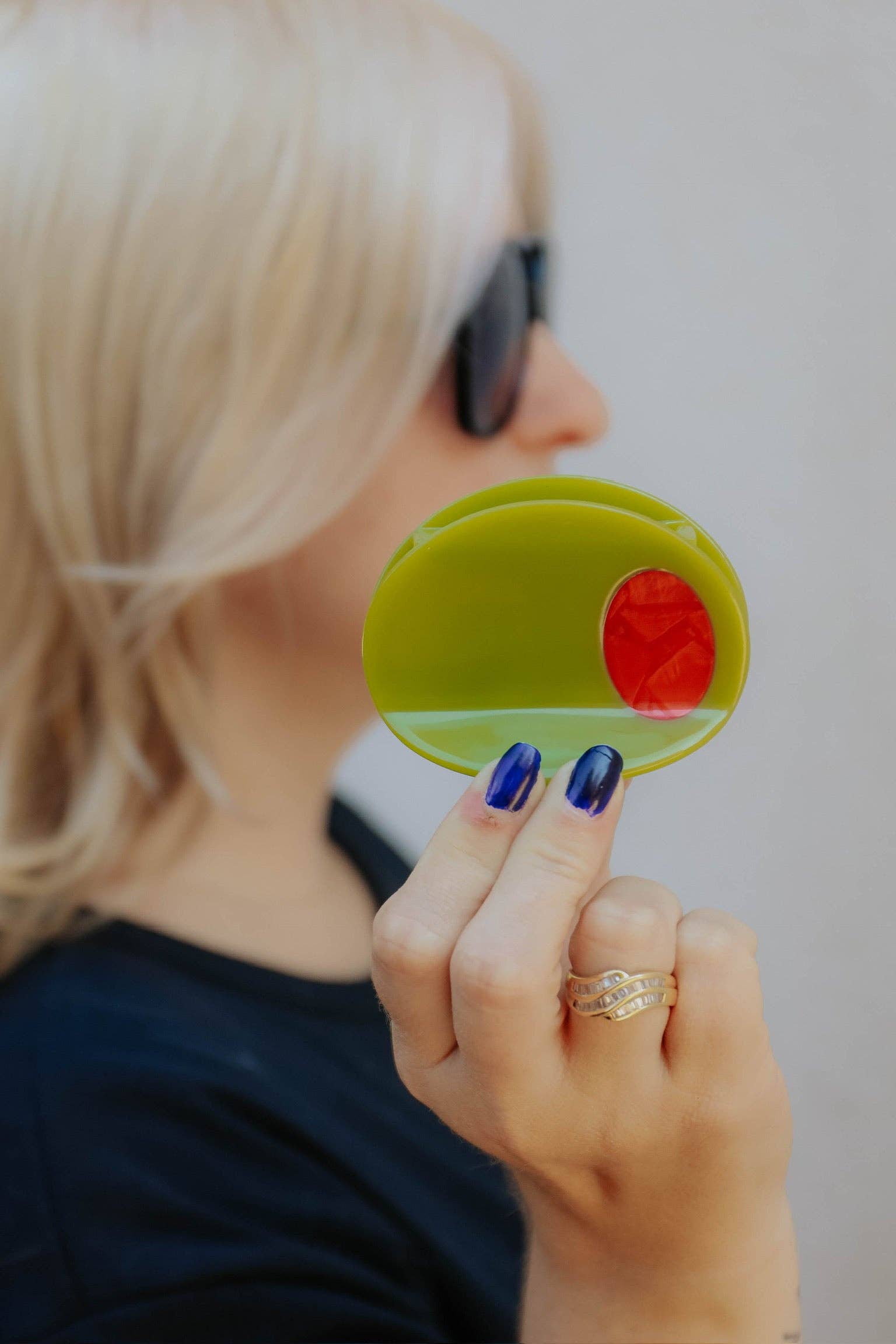 Person holding a olive hir claw object with a red center against a neutral background