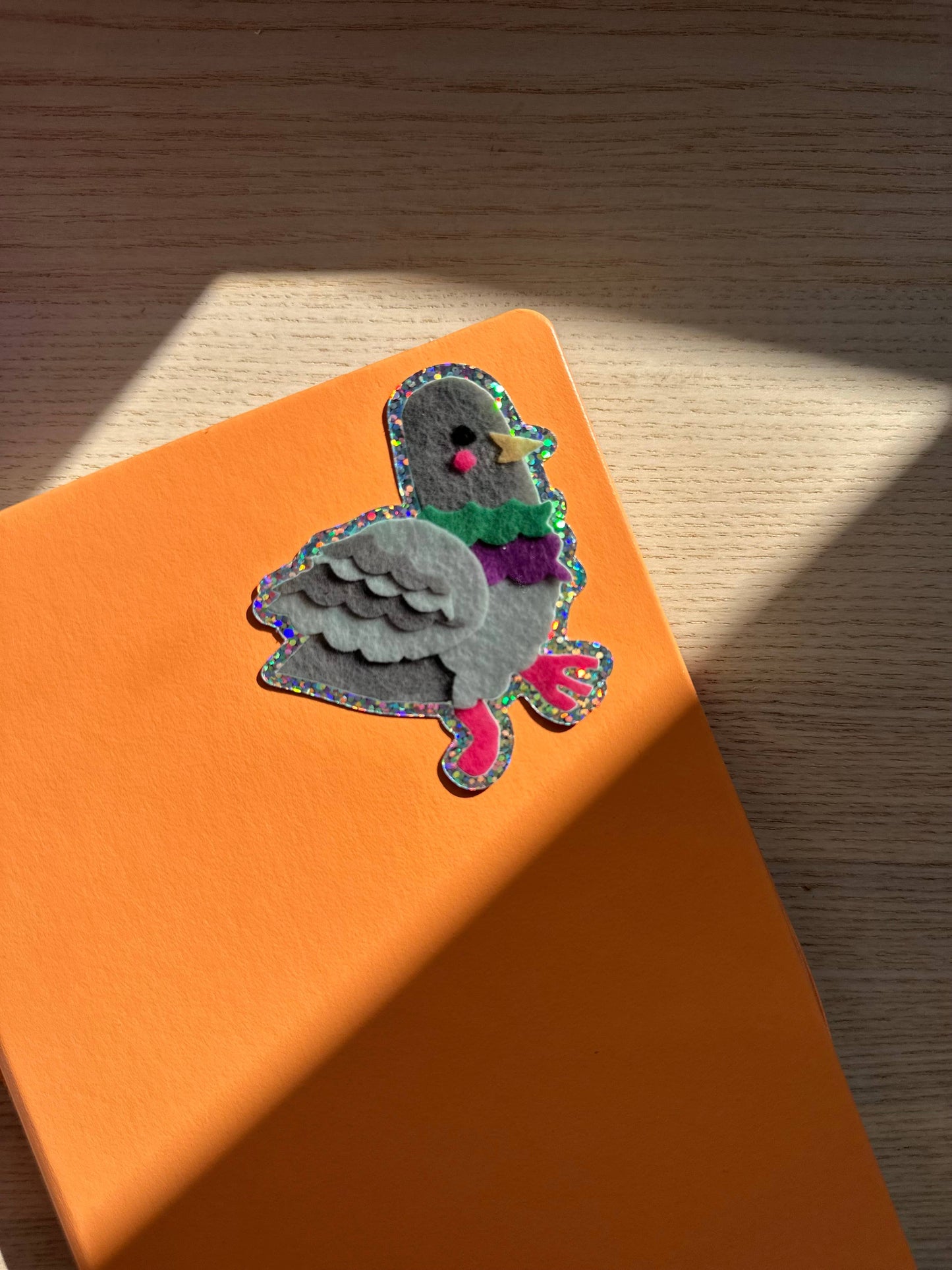 Pigeon glitter sticker on an orange surface