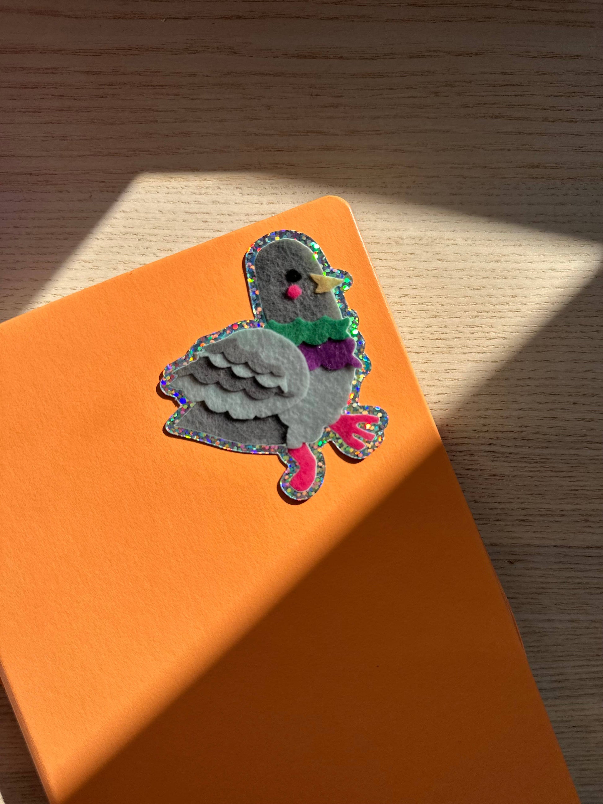 Pigeon glitter sticker on an orange surface