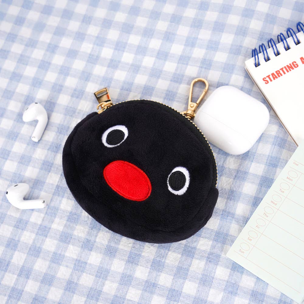 Black plush coin purse with a red nose and white eyes on a checkered tablecloth.