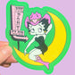 Sticker of betty boop on a moon with 'Pink Pony Club' sign, held against a purple background.